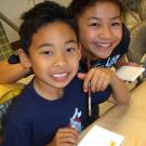 Julian Barker looks up from his artwork during a Campus Recreation activity, with staff member Nancy Nguyen looking over his shoulder.
