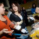 Photo: two women cooking over a stove in a busy place