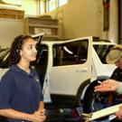 Man on right interviewing woman with Ford Explorer in the background with the hood up.