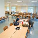 Two students sit in wide open room filled with new desk and new chairs, in new study space in Shields Library.