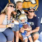 Photo: Jenny and Scott Seacrist and children in front of Aggie Athletics banner.