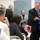 Classroom setting showing students seated and man hugging woman in the front
