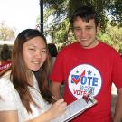 Woman with clip board with a man with a "vote" T-shirt