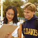 Photo: Man looking over woman's shoulder as she signs a petition