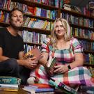 Brett and Erin Arnold sit on the floor of their bookstore with several books around them