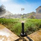 Sprinklers water a lawn in front of a house