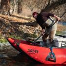 Leanne Knutson of Yurok Tribe leans over red pontoon boat to scoop up dead salmon from Klamath River