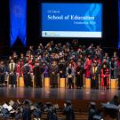 Graduation ceremony on stage with faculty and graduates in caps and gowns