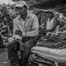 migrant workers under tarps in tent in black and white photo