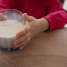 Child's hands hold a class of milk