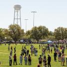 Crowd gathered on a field with a water tower in the background